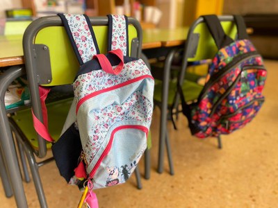 Fotografía d'un aula amb dues motxilles.